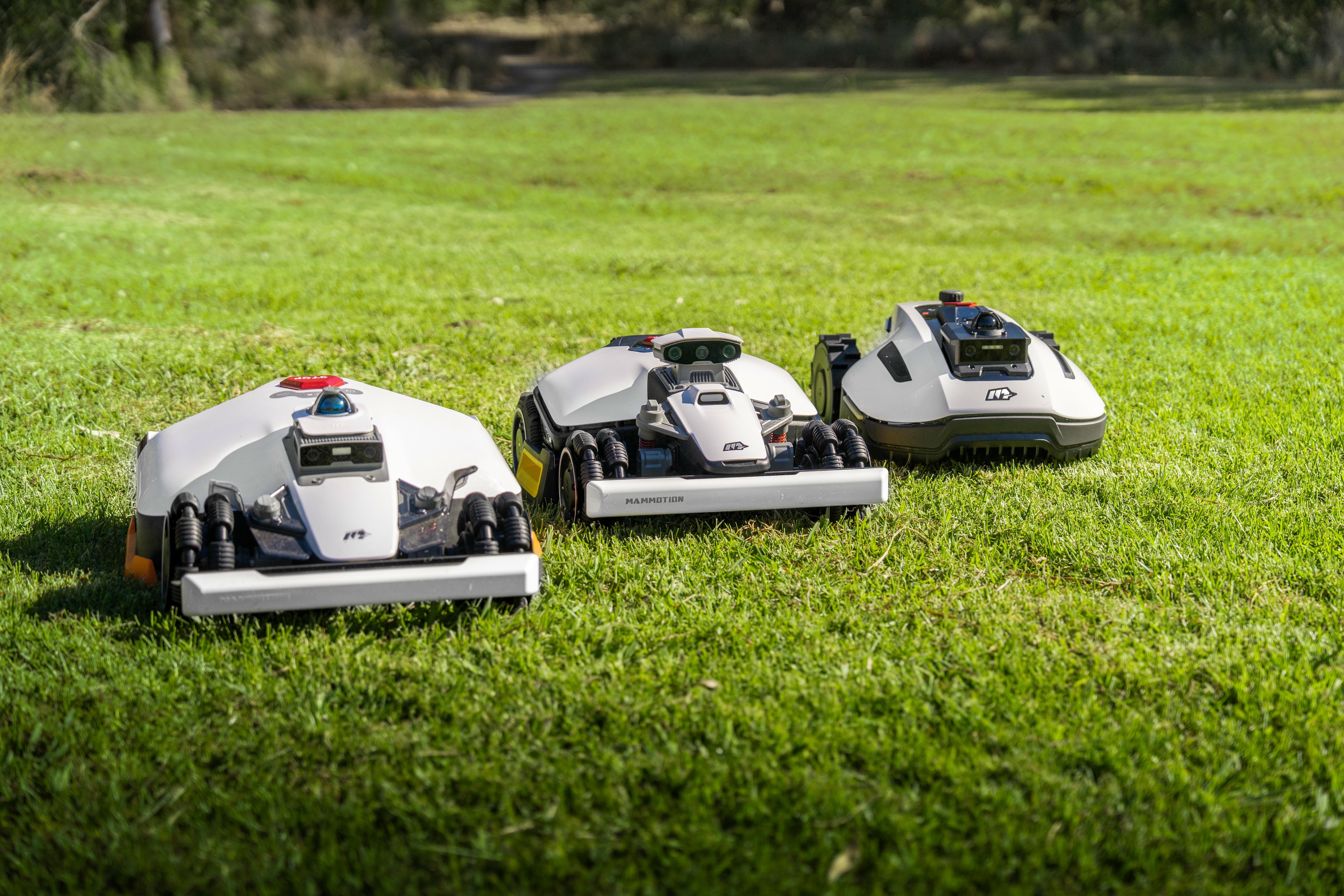 Three robotic mower models displayed together